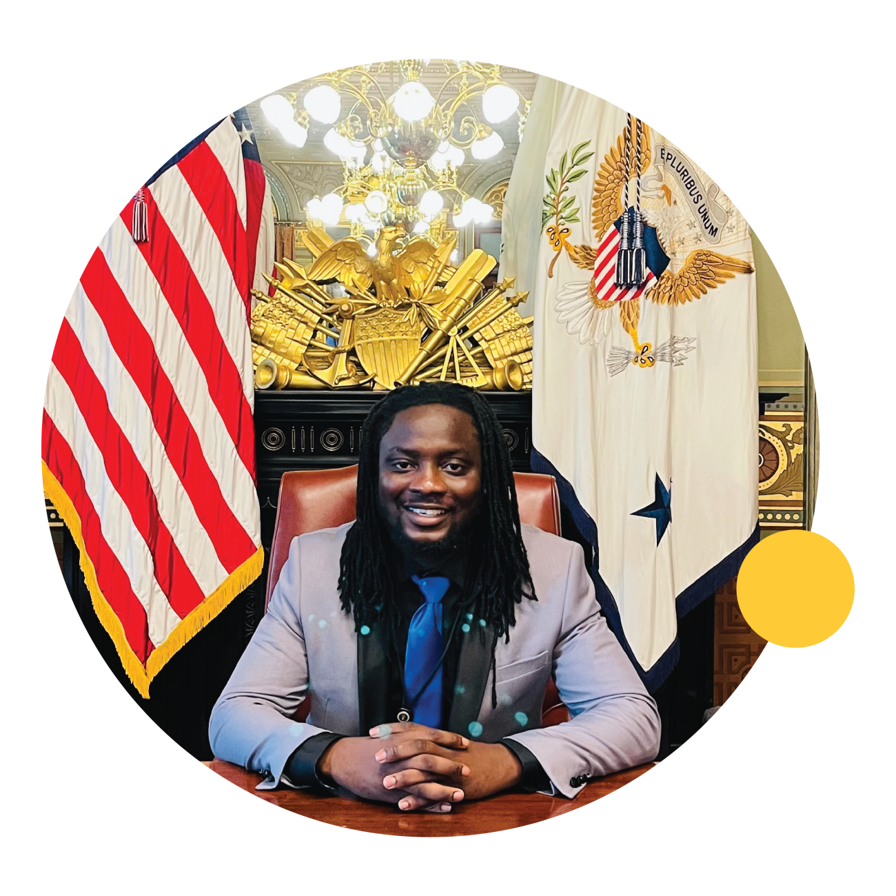 Prince Murray, a May 2021 ASU graduate, sits at a desk in front of the American flag.